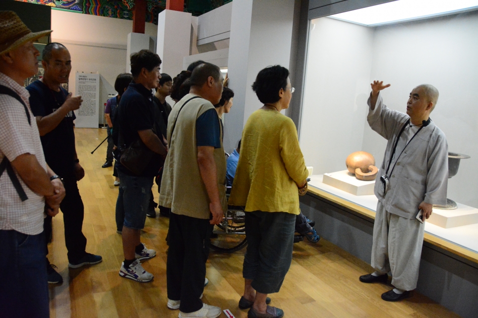 화엄사 성보박물관 부관장 무진스님이 서울에서 온 중증 장애인 불자들에게 성보박물관에 소장한 대형 목탁을 소개하고있다