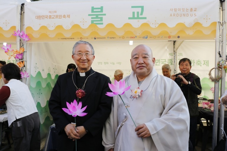 불교에서 준비한 연꽃 만들기 체험 부스 앞에서 총무원장 원행스님(오른쪽)과 김희중 대주교가 기념사진을 찍는 모습.