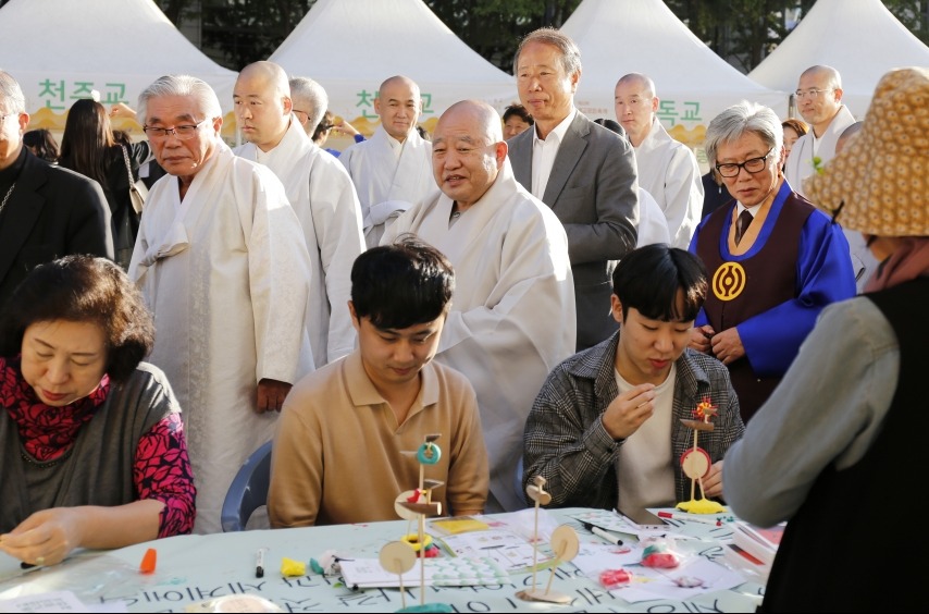 각 종교에서 마련한 체험 부스를 둘러보며 시민들과 함께 하고 있는 총무원장 원행스님과 종교 지도자들의 모습.