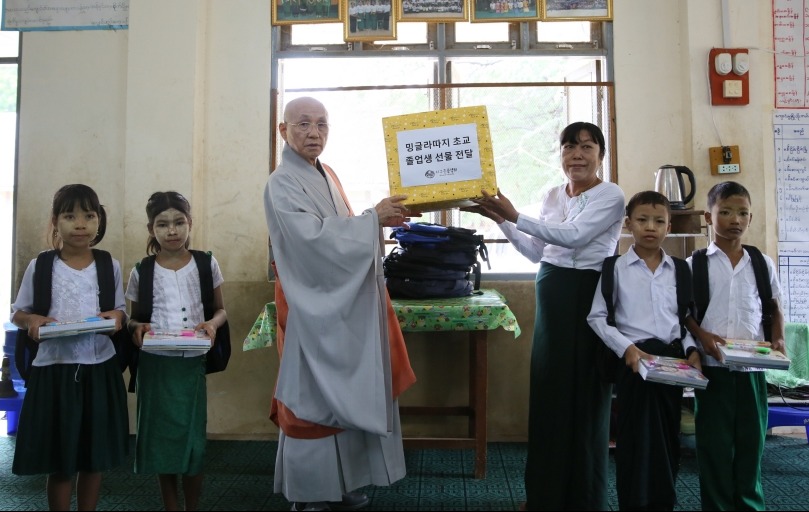 지구촌공생회 이사장 월주스님이 밍글라따지 초등학교 졸업생들을 위한 선물을 전달하고 있다.