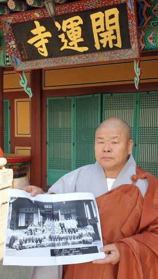 개운사 대각루 앞에서 97년 전 사진을 보고 있는 중앙승가대 총장 원종스님