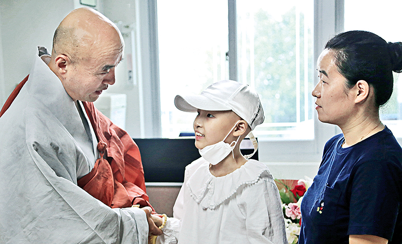 사회복지재단 상임이사 보인스님이 2019년 횡문근육종으로 투병 중인 김령 양과 김 양의 어머니에게 치료비를 전달하고 쾌유를 기원하는 모습.