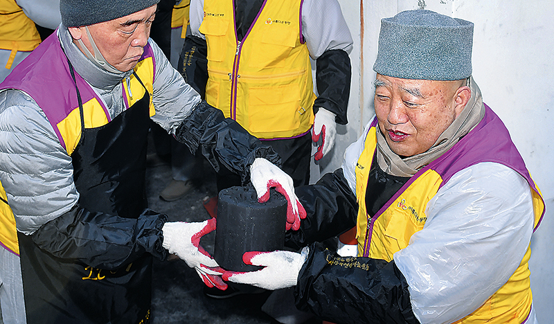 지난해 12월 서울 상계동 희망촌을 찾아 솔선수범 연탄 릴레이를 하는 총무원장 원행스님(오른쪽)의 모습. 불교신문