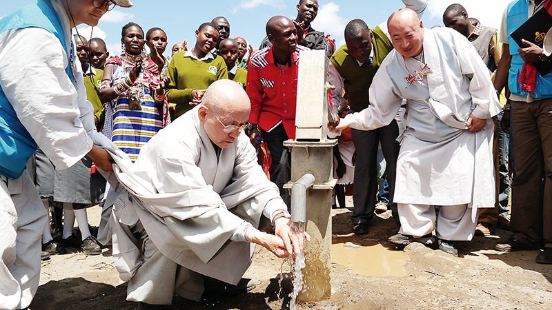 지구촌공생회가 아프리카 케냐 지역에 건립한 우물에서 나오는 깨끗한 물로 직접 손을 씻는 이사장 태공 월주 대종사(가운데) 모습.