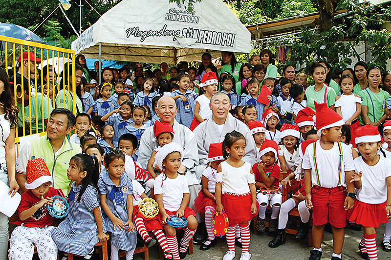 굿월드자선은행 대표 덕문스님(가운데 오른쪽)이 필리핀 빈민가 아이들을 위해 크리스마스 파티를 열어주는 모습. 종교를 초월한 자비행이 눈길을 끈다.
