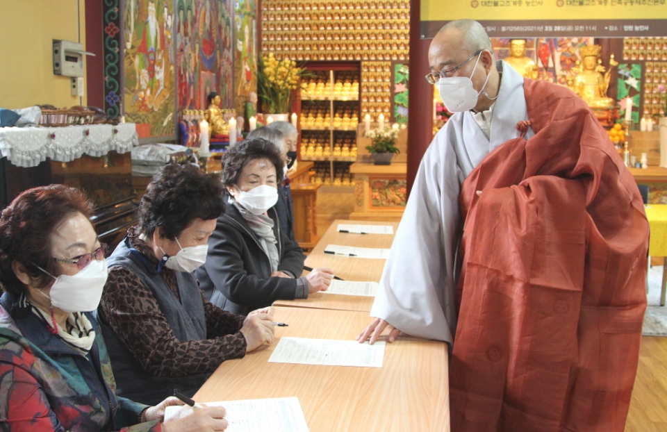 능인사 주지 지상스님이 민추본 정기후원 신청서를 작성하는 신도들을 격려하는 모습.