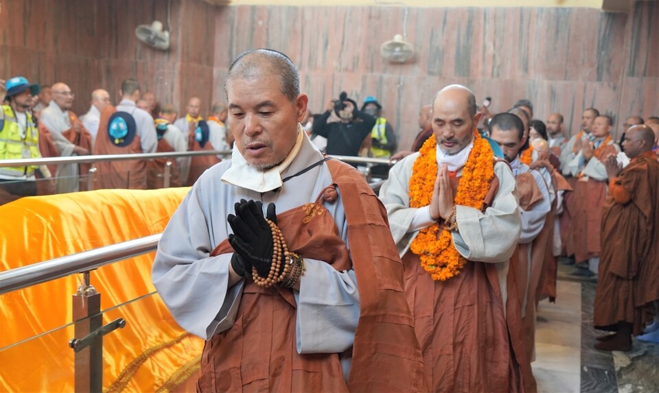 열반당 부처님에게 가사를 공양하고 합장 기도하는 인도순례 대중.