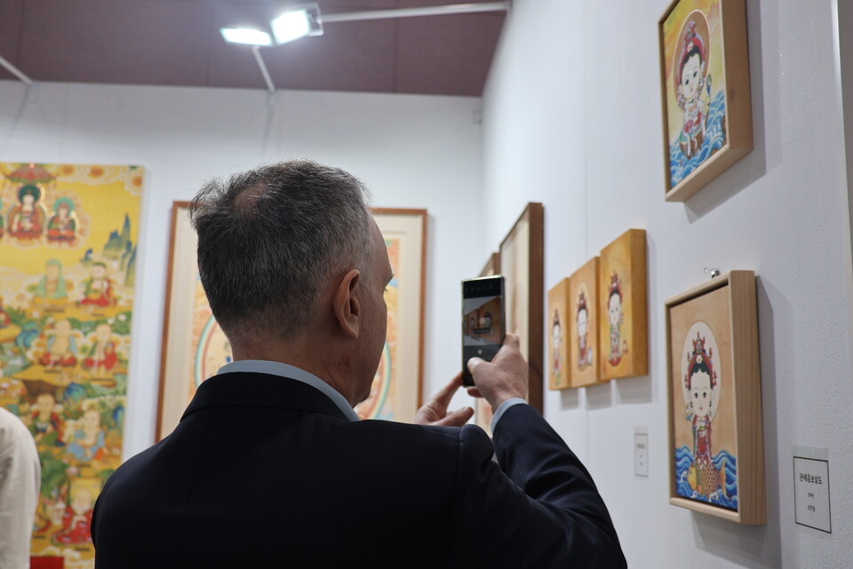 “큐트 붓다!”. 해밀턴 씨가 부처님을 귀엽게 형상화한 김지원 작가의 그림을 카메라에 담고 있다.