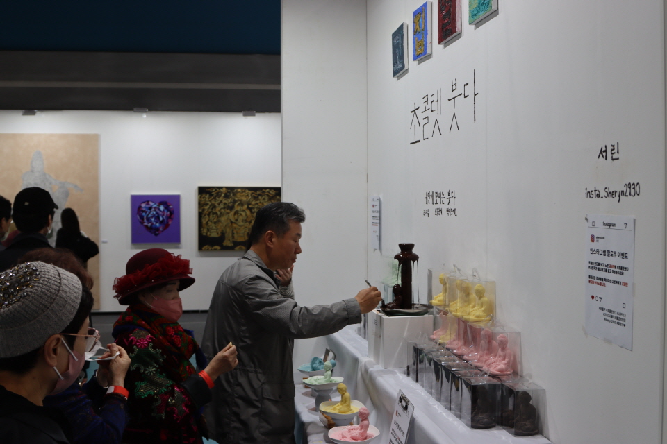 다소 파격적인 전시 제목을 붙인 '초콜렛 붓다' 부스에서 관람객들이 과자를 초콜릿에 찍어 먹고 있다.