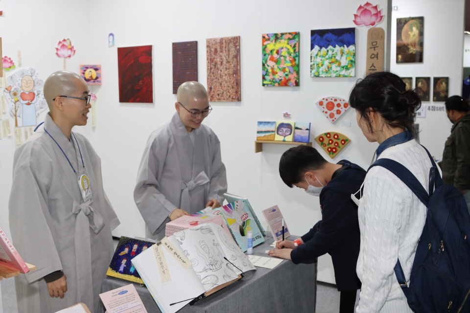 창작집단 일상다감사 지도법사 한산스님과 무여스님의 '날마다부처님' 부스에서 어린이가 소원지를 쓰고 있다.