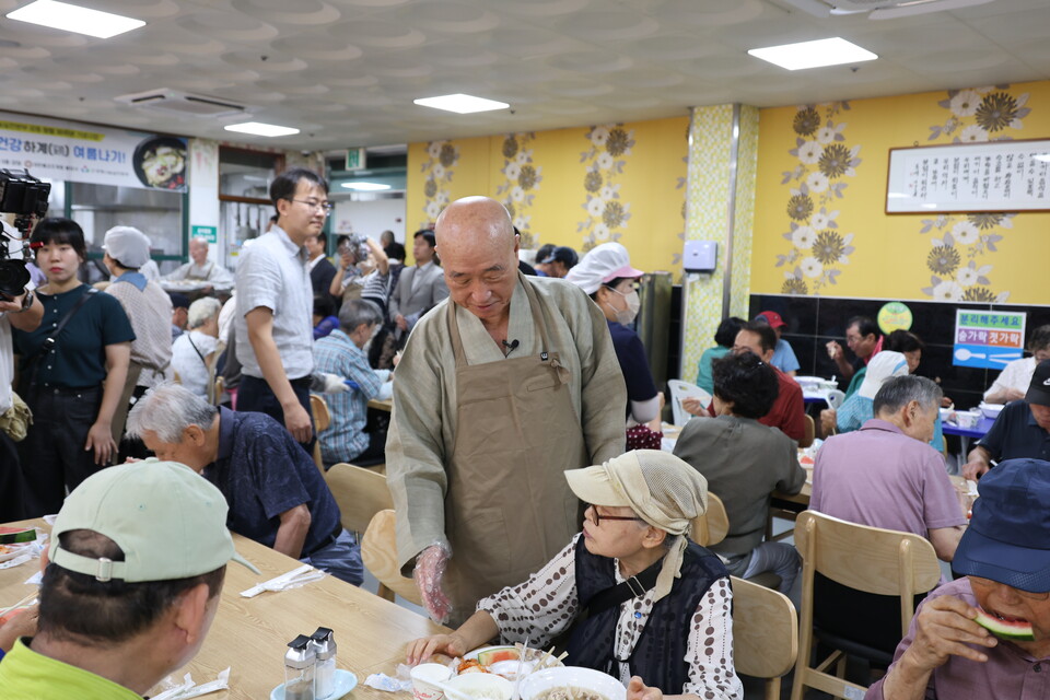 생명나눔실천본부 이사장 일면스님이 송산노인종합복지관 이용자 어르신에게 여름 보양식을 대접하는 모습.