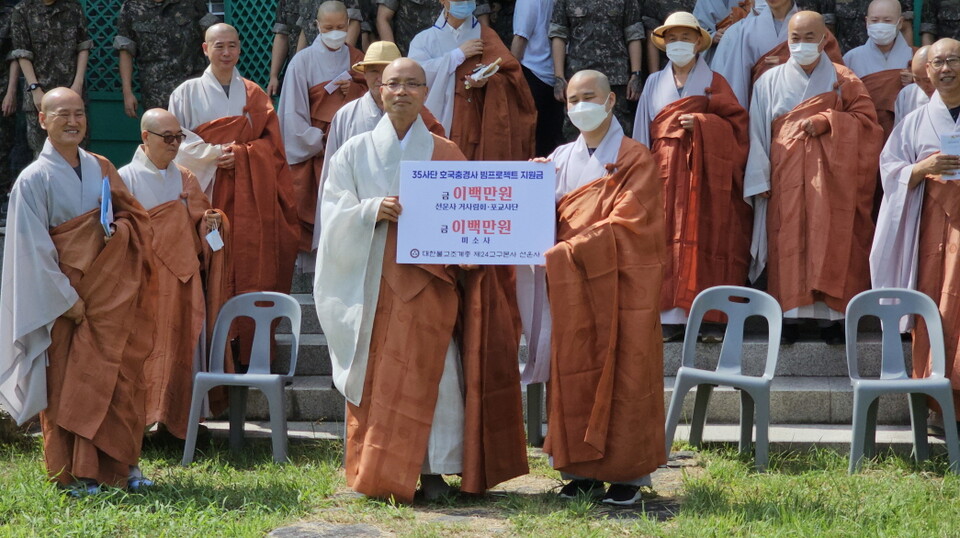 선운사 주지 경우스님이 호국충경사 정지운군법사에게 기탁금 증서를 전달하고 있다.