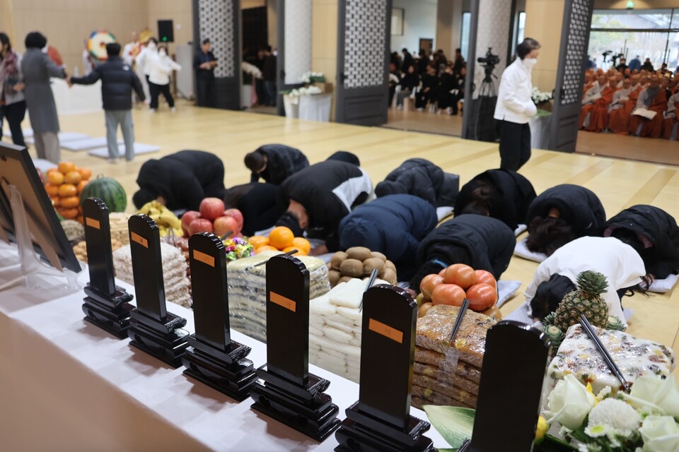 유가족들이 희생자 위패와 영정 앞에서 절하고 있다.