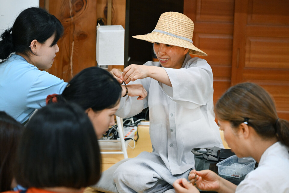 지도법사 심훈스님이 한 참가자에게 단주를 걸어주고 있다.