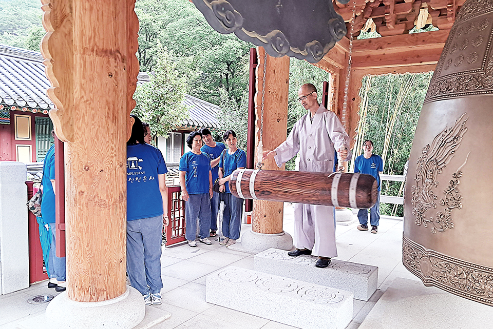 천은사 템플스테이에 참여한 사람들에게 스님이 타종법을 가르쳐주고 있다.